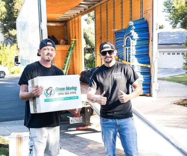 Movers at Grace Moving holding their thumbs up in front of a prepped moving truck before a move.